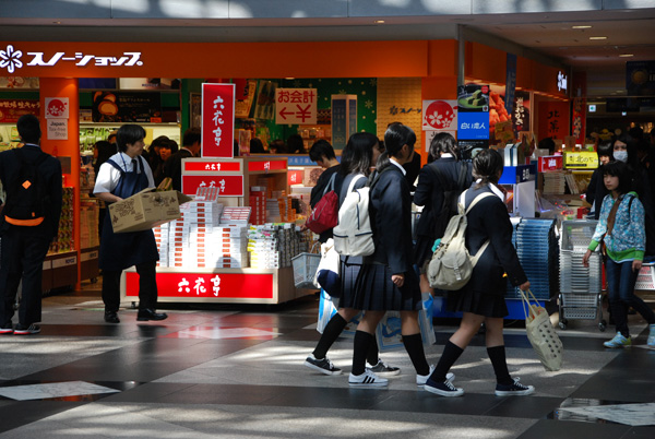 一群学生经过机场商场大厅的手信土产店，有出售白色恋人及六花亭。